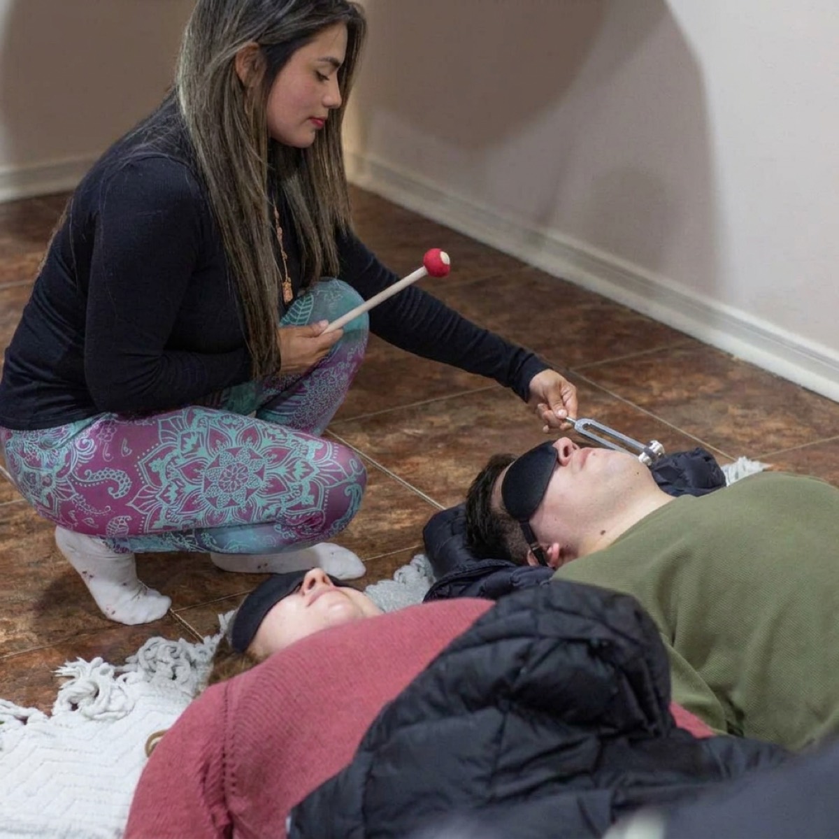 Bárbara aplicando un diapasón a una persona recostada con antifaz